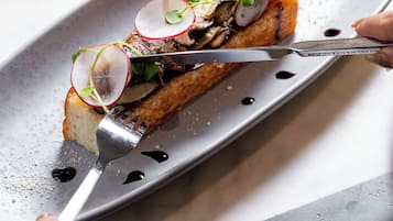 A person cutting a dish with a fork on a plate.