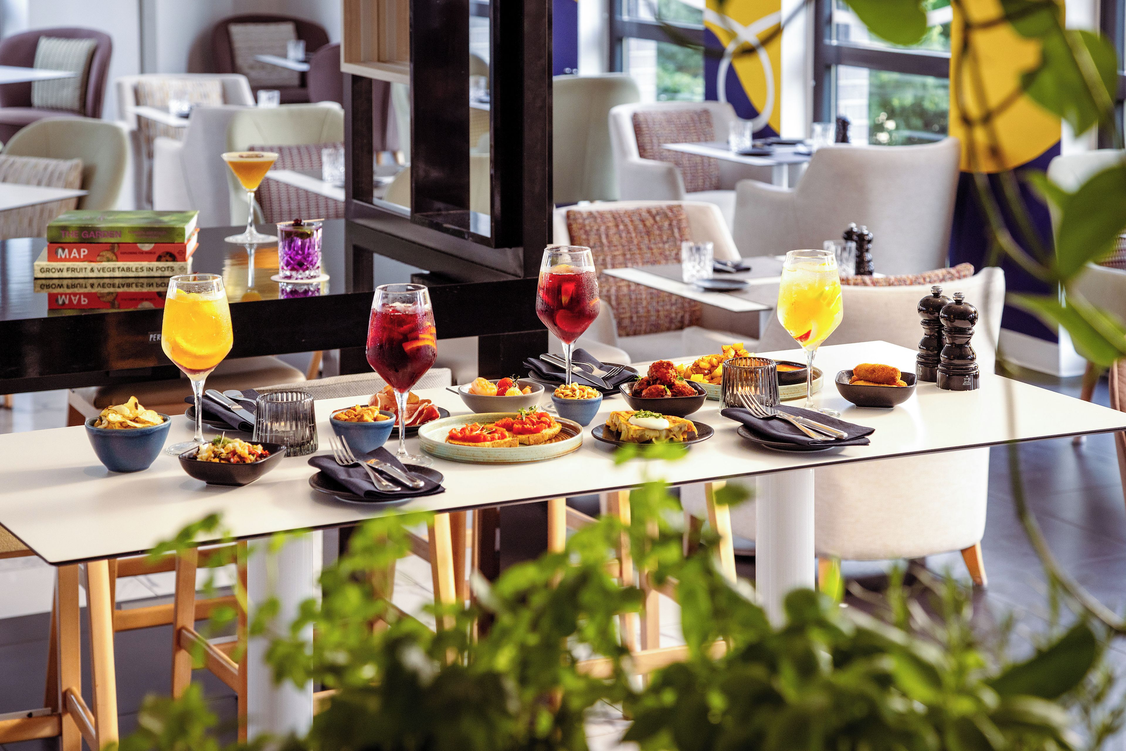 A dining table set with various dishes, drinks, and a selection of books.