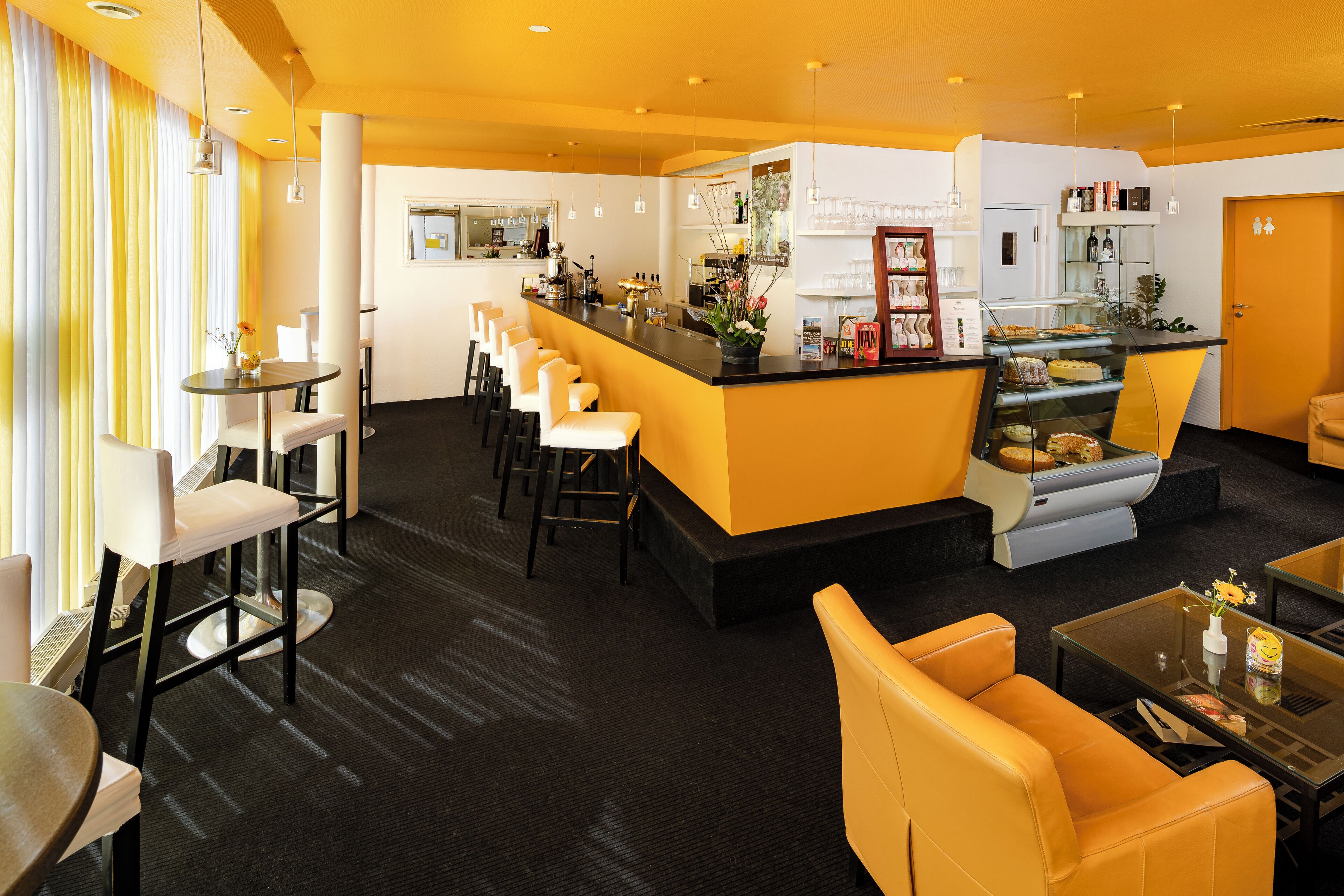 A hotel lobby with a bar area, seating arrangements, and a reception desk.