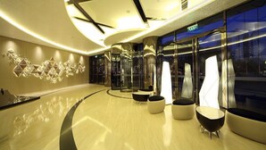 Eine moderne Lobby mit gewölbter Decke, Glaswänden und zeitgenössischen Sitzbereichen.