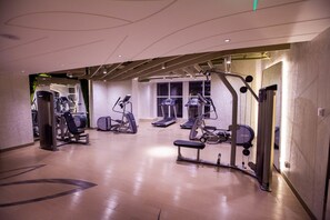 Ein Fitnessraum mit unterschiedlichen Trainingsgeräten, darunter Laufbändern und Kraftmaschinen, sowie einer Trainingsbank.