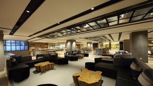 Ein moderner Loungebereich mit Sofas, einem Couchtisch und einem Essbereich mit Tischen und Stühlen.
