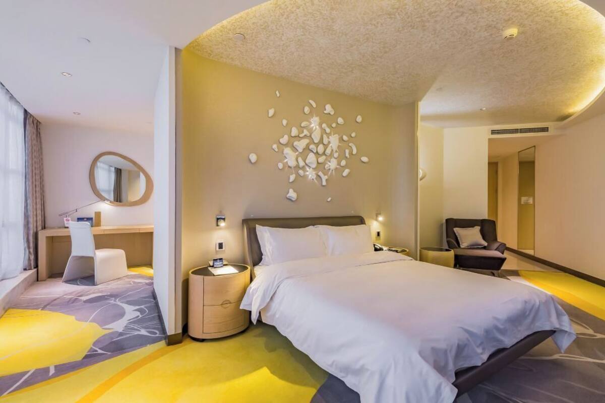 Une chambre d’hôtel moderne avec un grand lit, des tables de chevet, un bureau et une chaise.