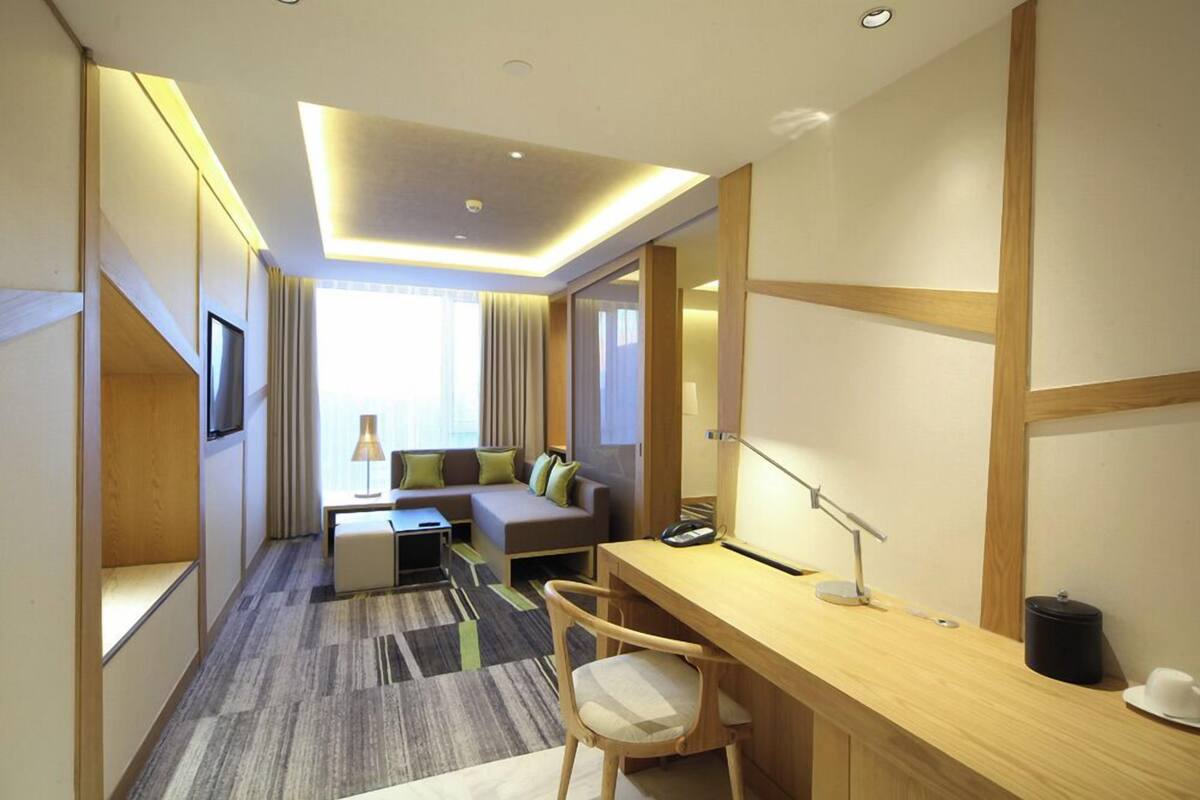 Une chambre d’hôtel équipée d’un bureau, d’une chaise, d’un canapé et d’un grand miroir.
