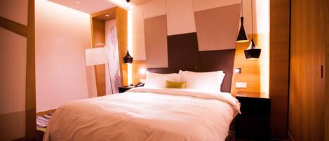 A modern hotel room with a large bed, bedside tables, and a unique wall design.