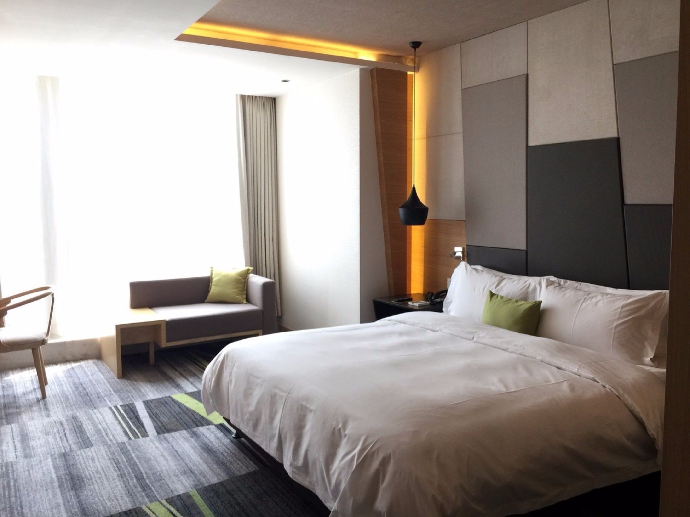 Quarto de hotel com uma cama grande, um sofá, uma escrivaninha e uma cadeira.