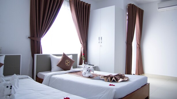Ett hotellrum med två sängar, en garderob och ett fönster med gardiner.