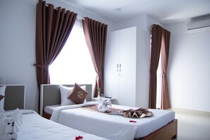 A hotel room with two beds, a wardrobe, and a window with curtains. - Poetic Hue Hotel (Hue)