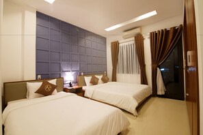 A hotel room with two beds, a large wall panel, a nightstand with a lamp, and a view of the outside through a window with curtains. - Poetic Hue Hotel (Hue)