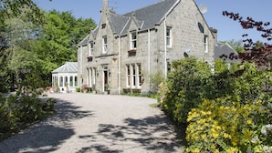 A stone building with a gravel driveway and a covered walkway. -  Ravenscourt Guest House (Grantown-on-Spey)