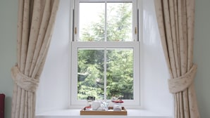 A window with a view of trees, curtains, and a tray with items. -  Ravenscourt Guest House (Grantown-on-Spey)