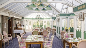 A conservatory with tables set for dining, chairs, and hanging lamps. -  Ravenscourt Guest House (Grantown-on-Spey)