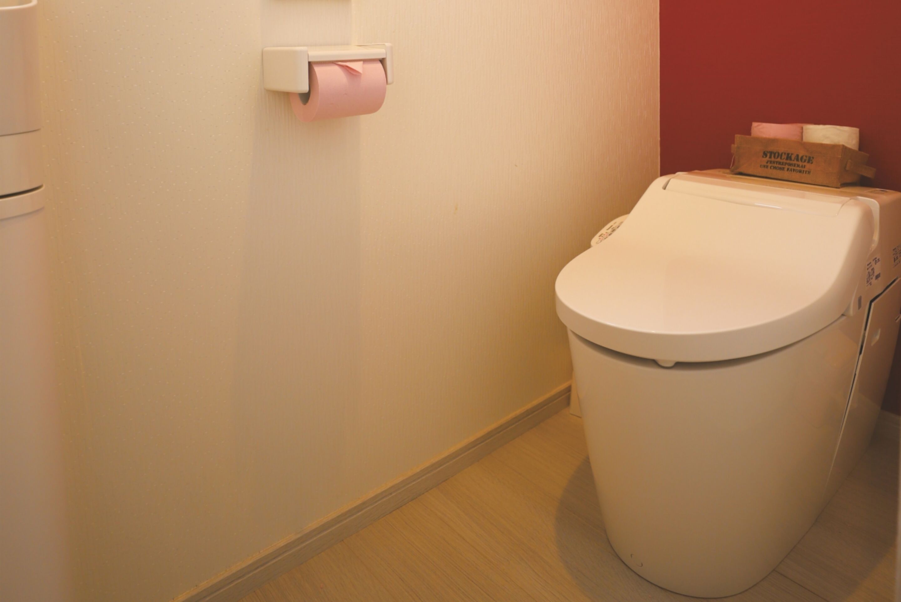 A toilet with a paper towel dispenser and a box of tissues on top.