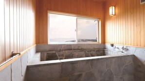 A stone bathtub with a view of the sea through a window. - Churamui Terrace (Motobu)