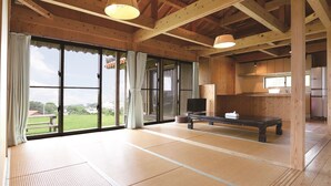 A spacious room with tatami mats, a television, and a kitchen area. - Churamui Terrace (Motobu)