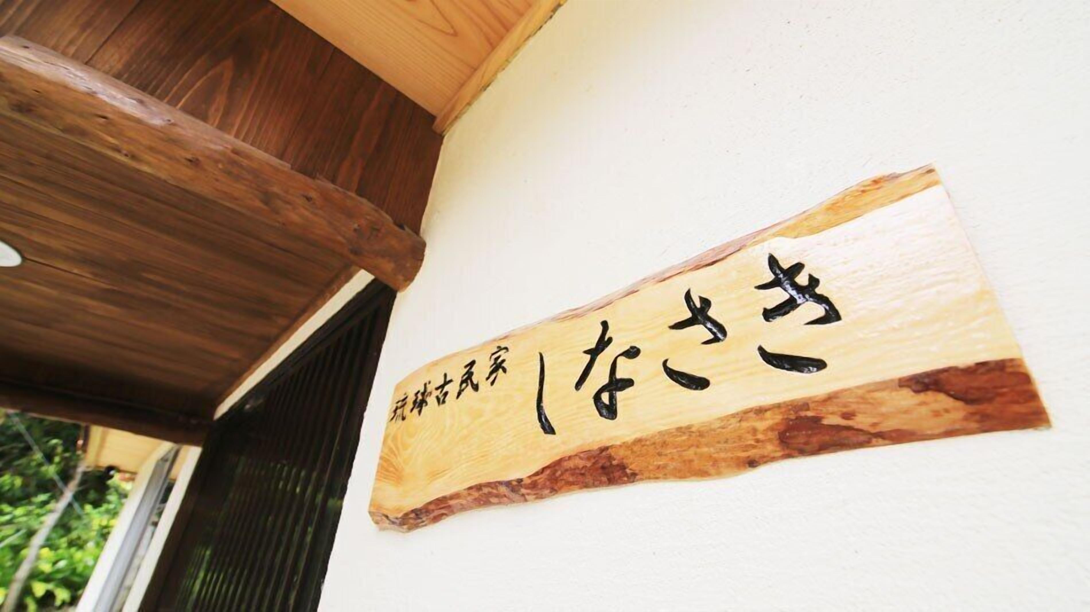 Un letrero de madera con caracteres japoneses sobre una pared blanca.