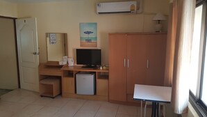 A compact hotel room with a kitchenette, a television, a refrigerator, and a window with curtains. - Sandman hotel and Sports bar (Pattaya)