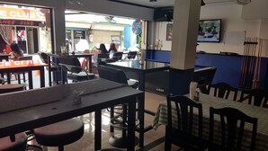 A restaurant with tables and chairs, a counter, and a TV screen. - Sandman hotel and Sports bar (Pattaya)