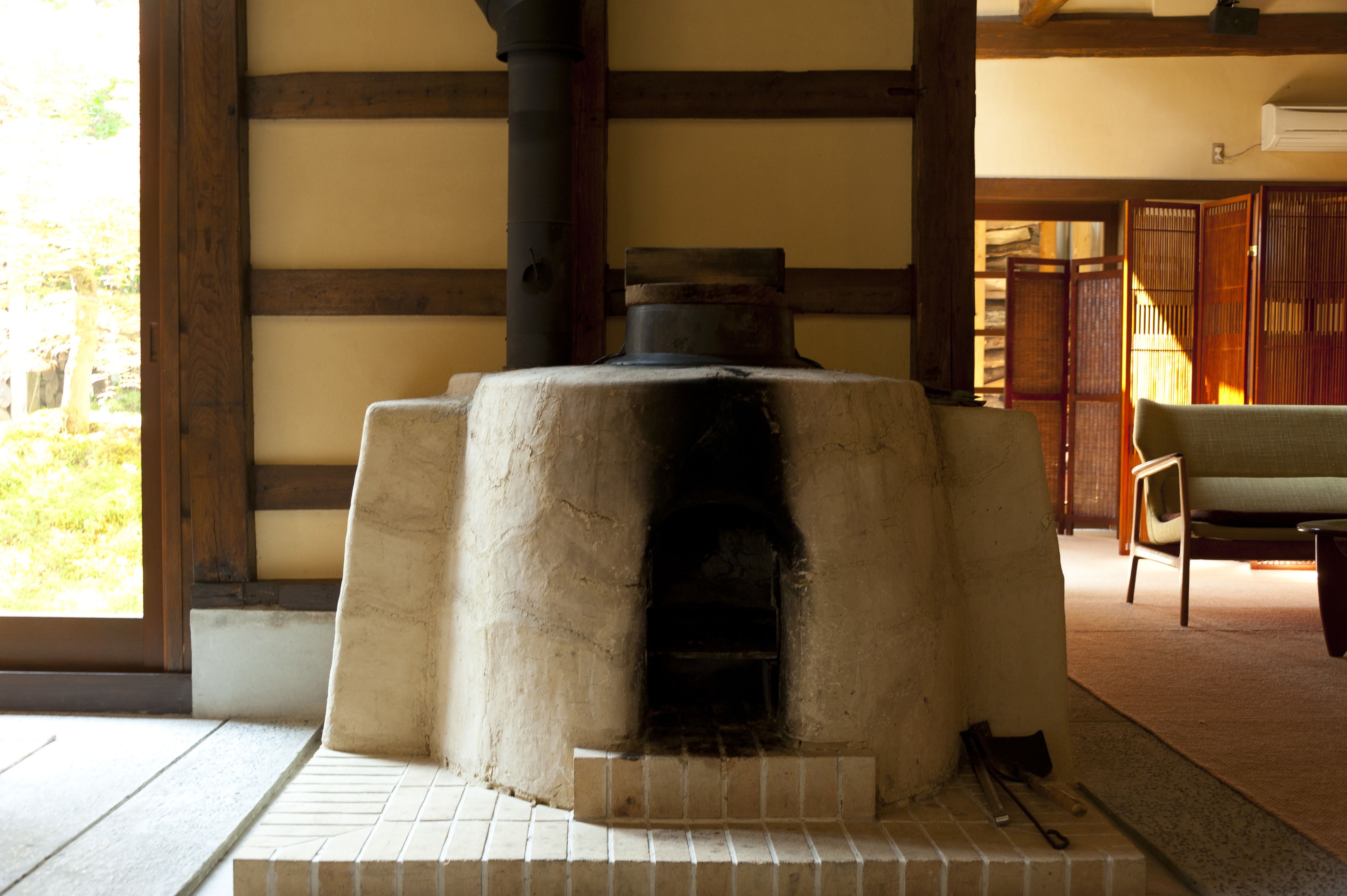 A traditional Japanese room with tatami flooring, a stone hearth, and a sliding door.