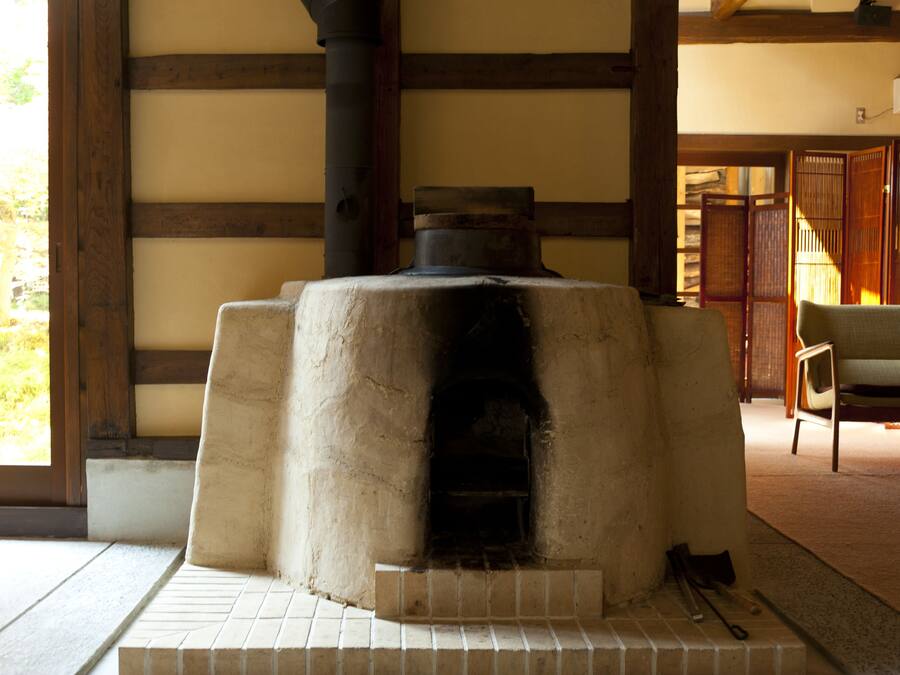 A traditional Japanese room with tatami flooring, a stone hearth, and a sliding door.