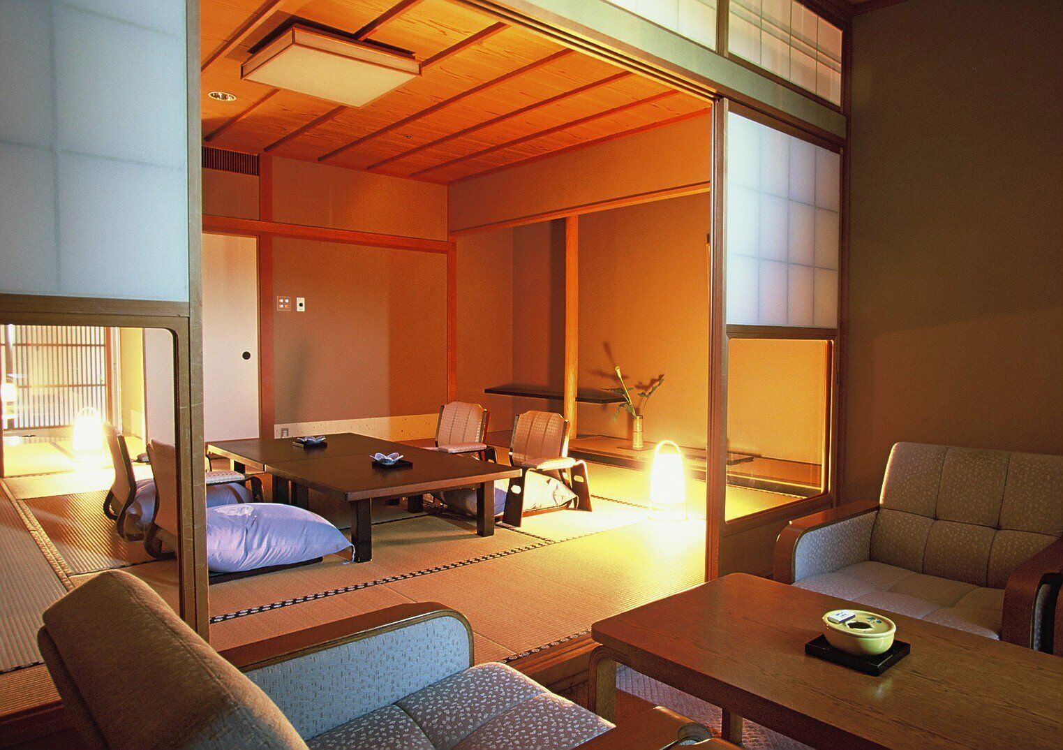 Una habitación tradicional japonesa con suelo de tatami, una mesa baja y disposición de asientos.