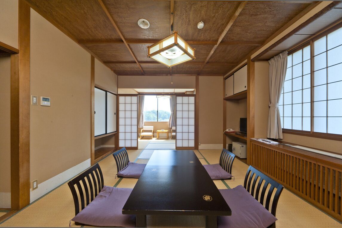 Una habitación japonesa tradicional con suelo de tatami, una mesa baja y puertas correderas que dan a un balcón.