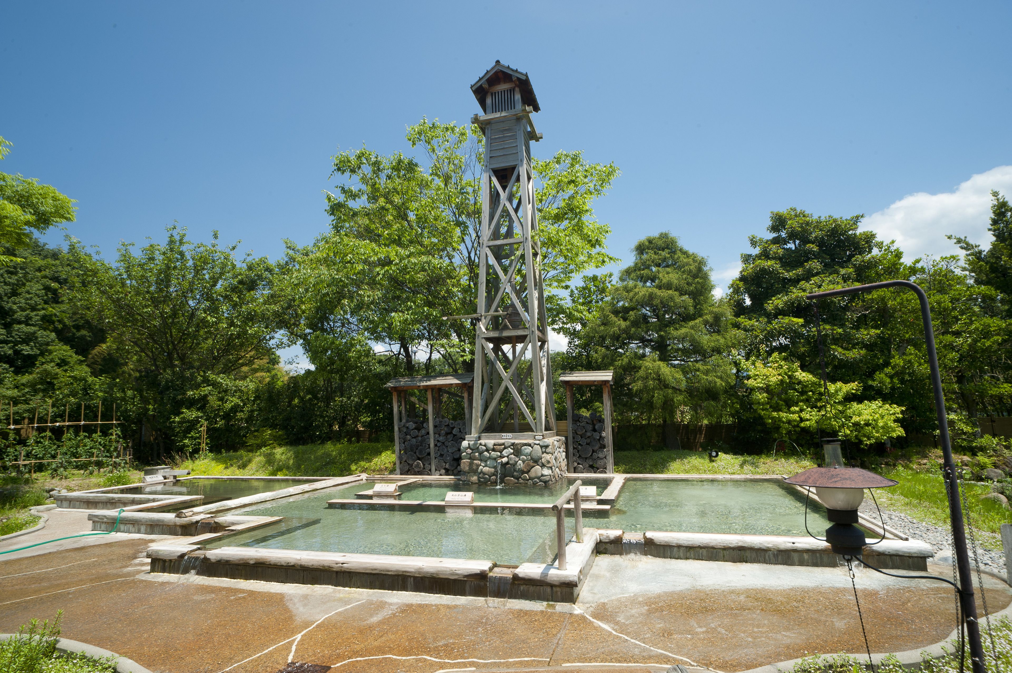 Ein traditionelles japanisches Onsen mit Steingrotquellen und einem hölzernen Turm.