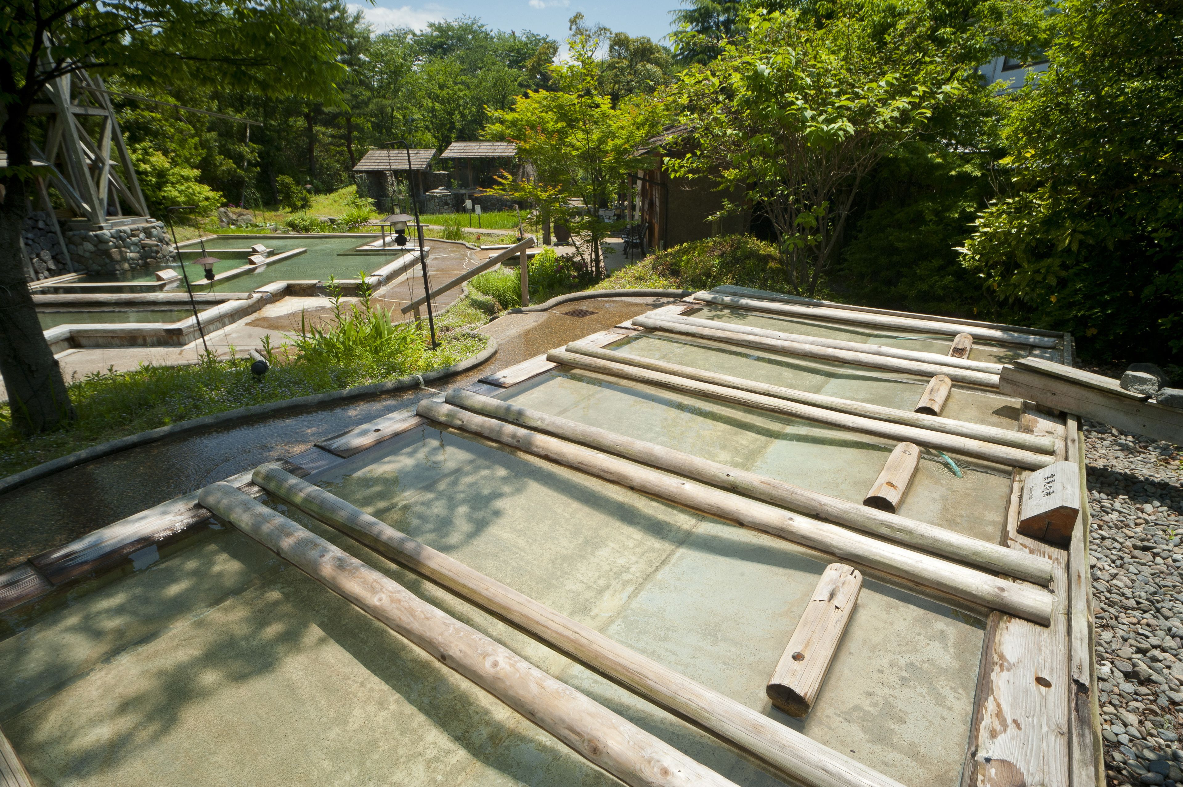 Ein traditionelles japanisches Onsen mit Holzbadewannen und einem Steinelement.