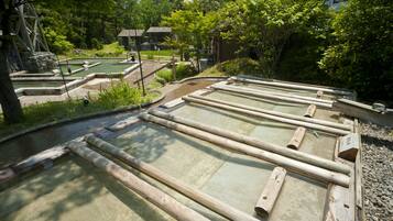 Ein traditionelles japanisches Onsen mit Holzbadewannen und einem Steinelement.