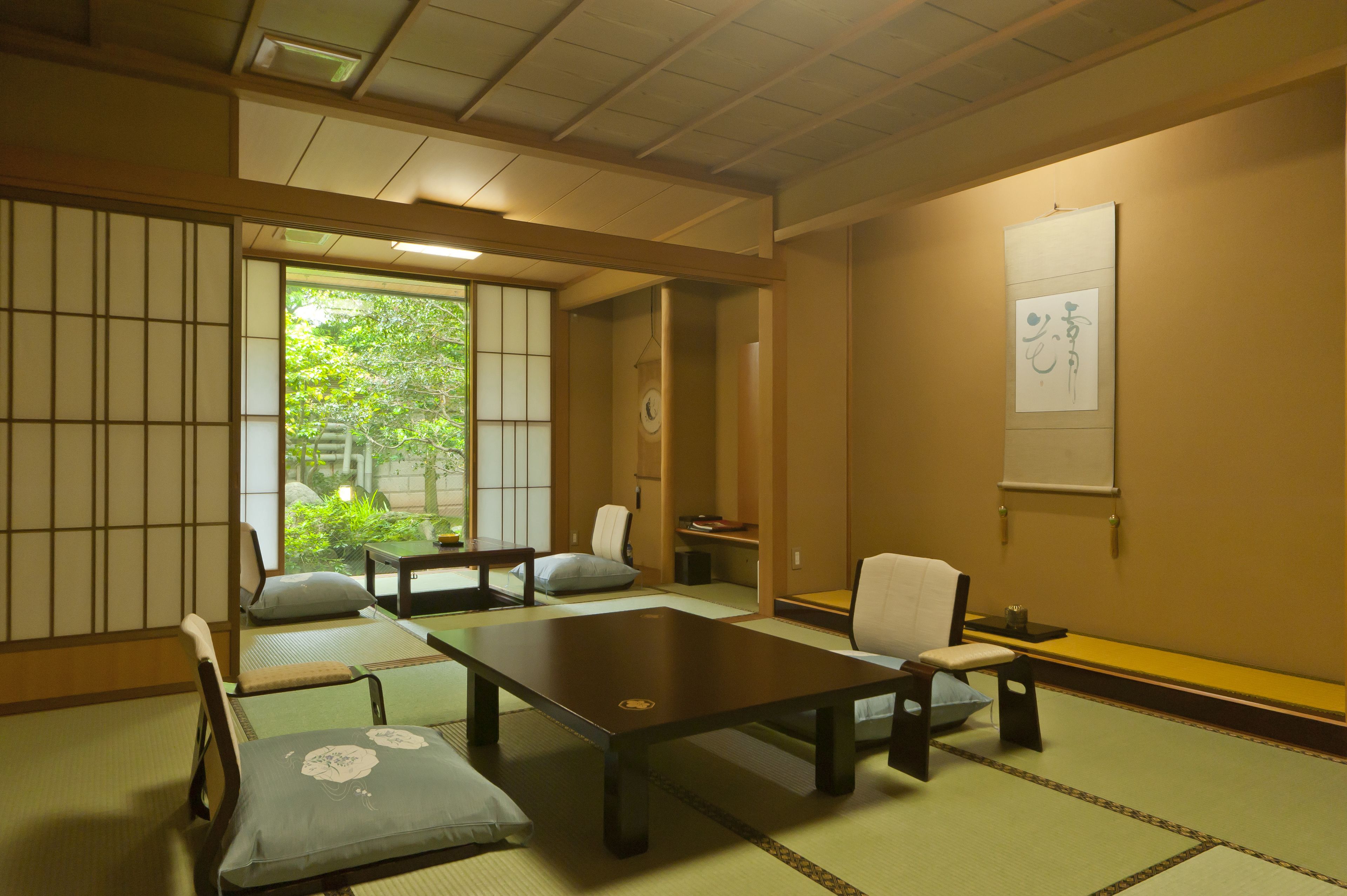 Una habitación japonesa tradicional con suelo de tatami, mesas bajas y puertas correderas shoji.