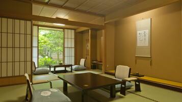 Una habitación japonesa tradicional con suelo de tatami, mesas bajas y puertas correderas shoji.