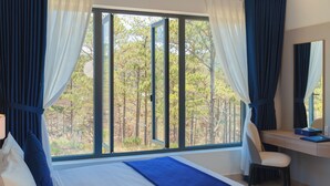 Un dormitorio con un ventanal grande, una cama, un escritorio y una silla.