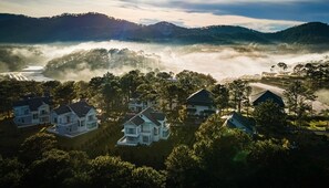Un barrio residencial con casas, un río y colinas al fondo.