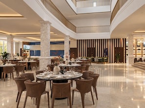 A spacious hotel lobby with multiple dining tables, comfortable seating, and a high ceiling with a skylight. - Tea Resort Dalat by Doi Dep (Da Lat)