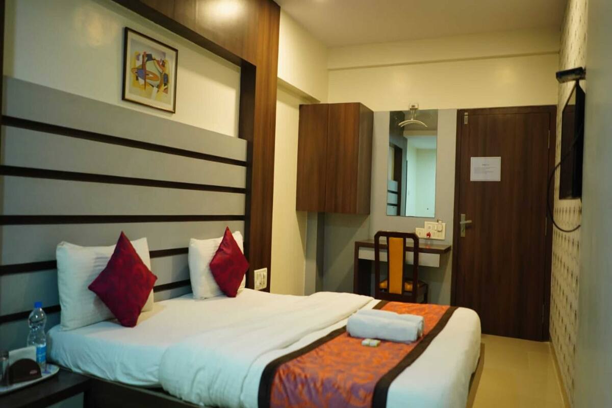 A hotel room with a bed, a desk, a chair, and a wardrobe.