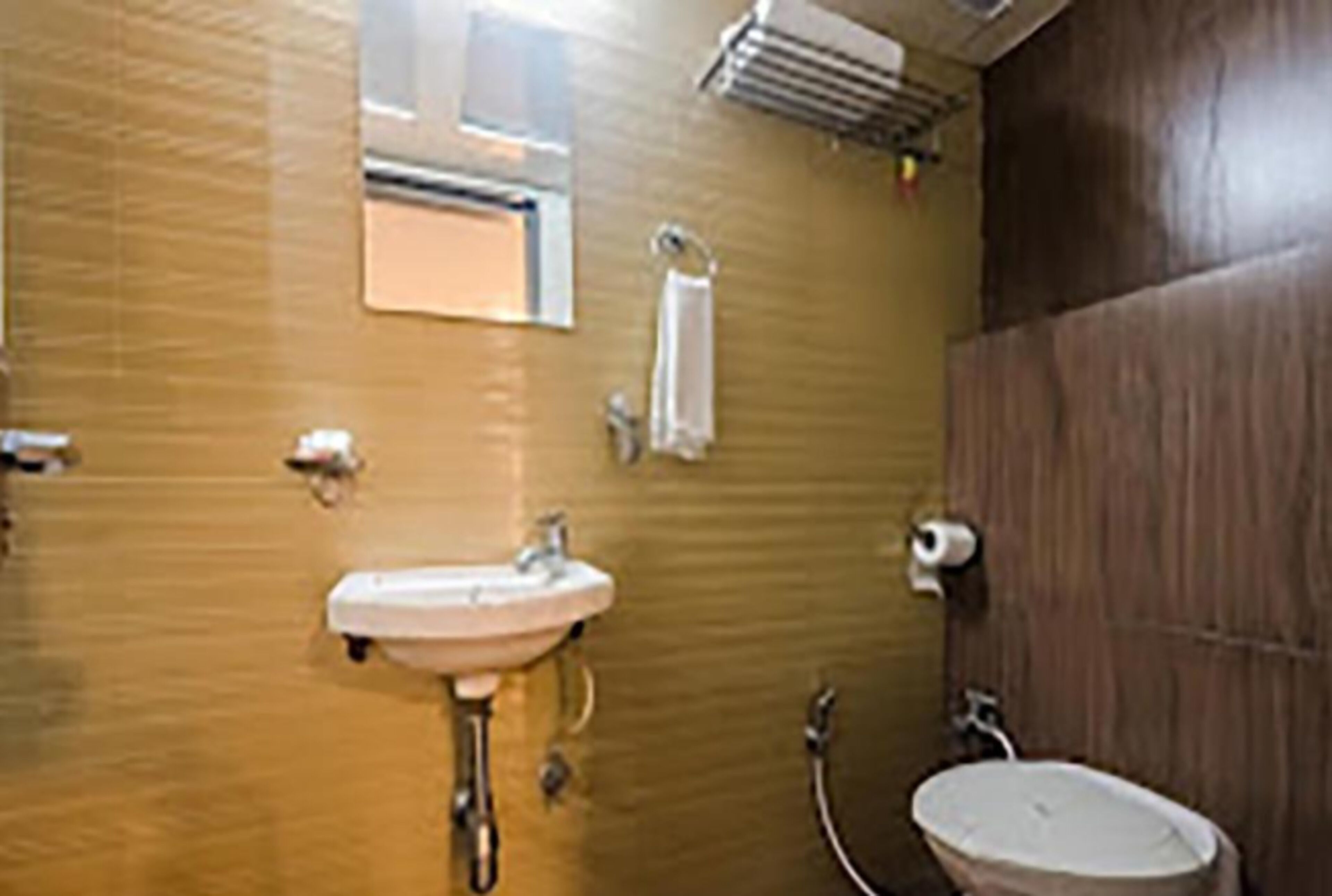 Een badkamer met een wastafel, spiegel, handdoekhouder en toiletrolhouder.