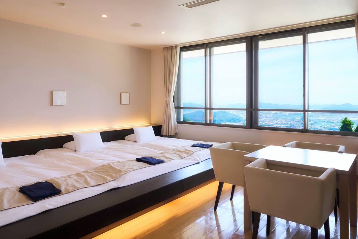 A hotel room with a large bed, a desk, and a window with a city view.