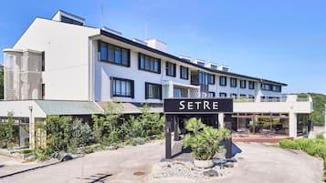 A modern hotel with a sign reading "SETRE" in front. It features a multi-story structure with large windows and a covered outdoor area with seating.