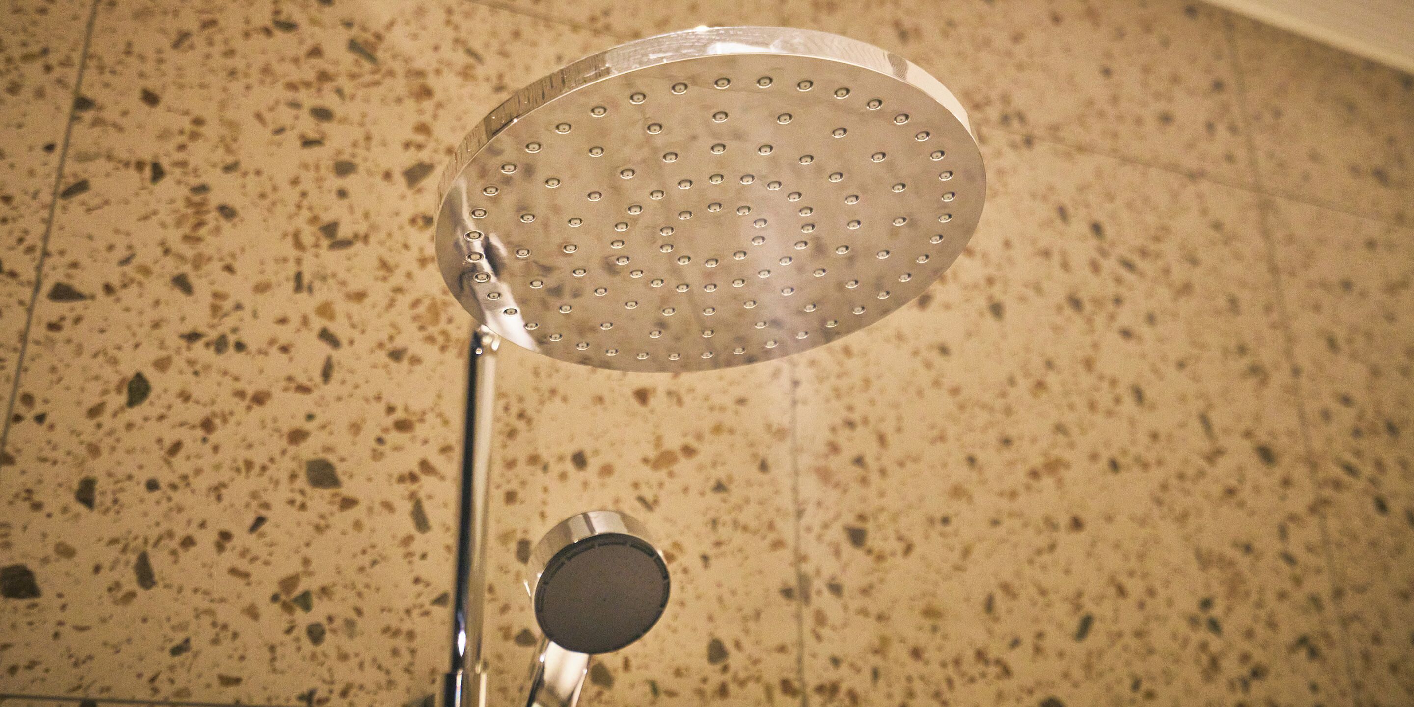Un cabezal de ducha con diseño circular y múltiples orificios, montado sobre una estructura metálica.