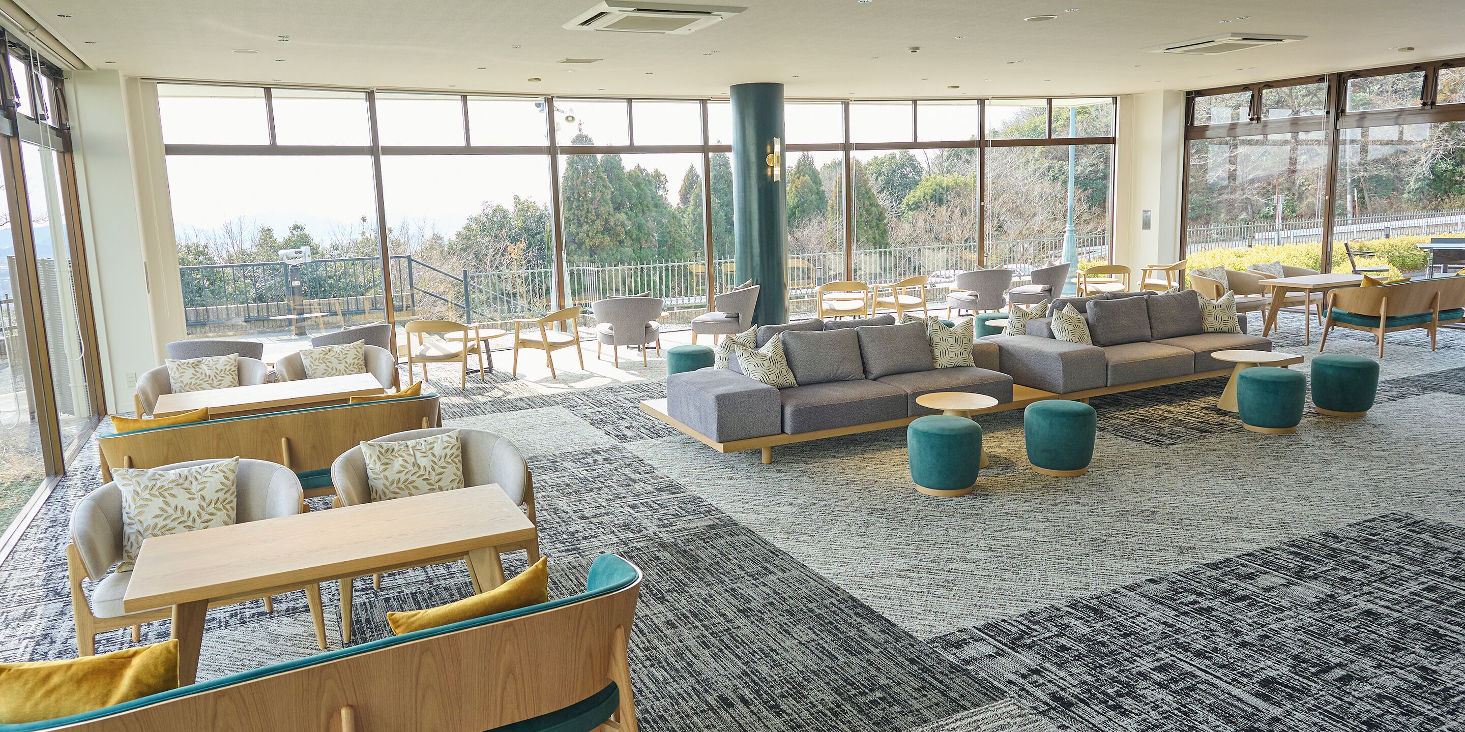 A spacious lounge area with multiple seating options, large windows offering views of the outdoors, and a modern interior design.