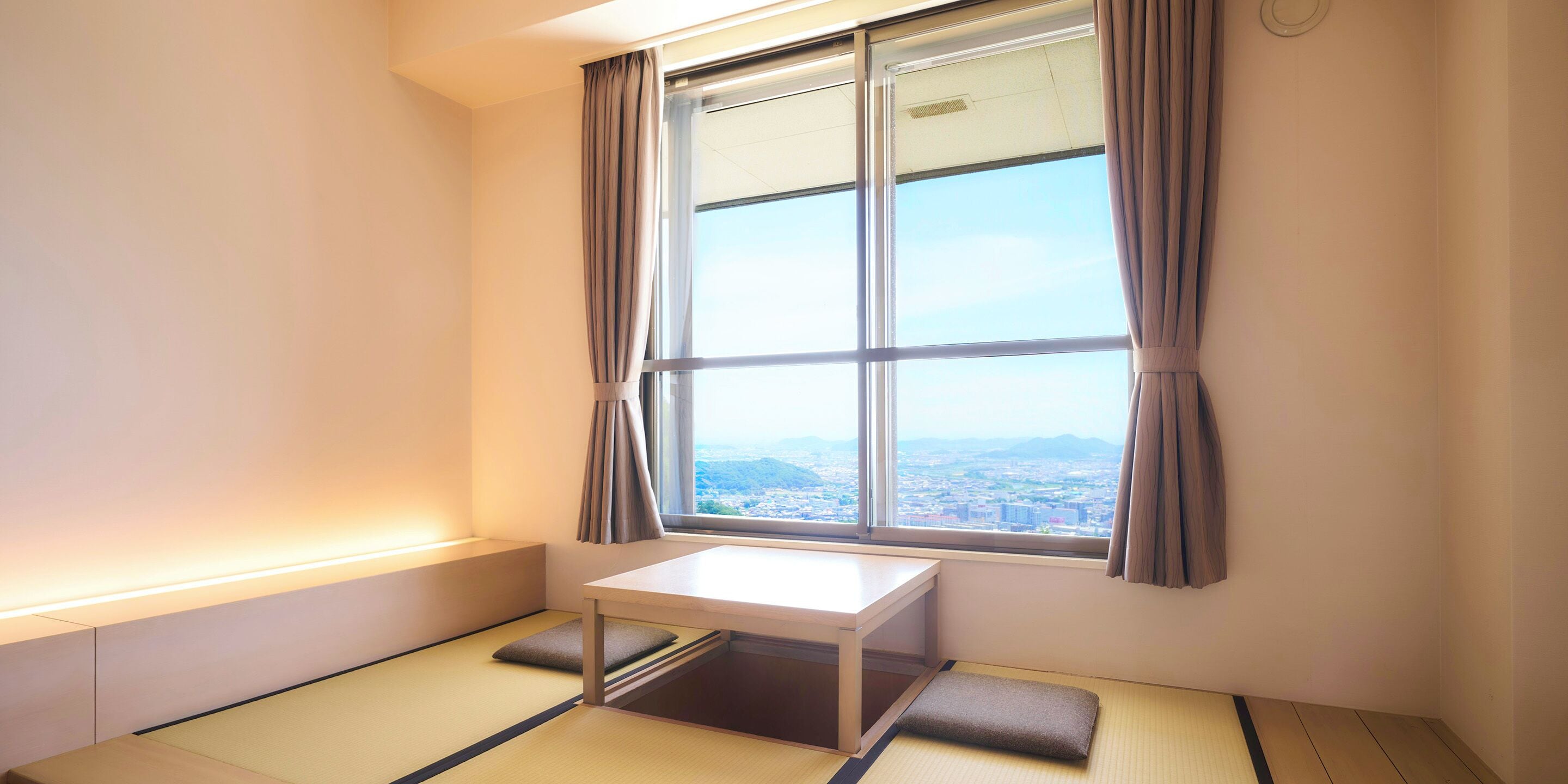 A room with tatami flooring, a low table, and a window with curtains.