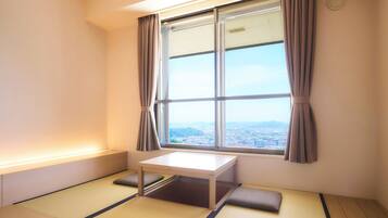 A room with tatami flooring, a low table, and a window with curtains.