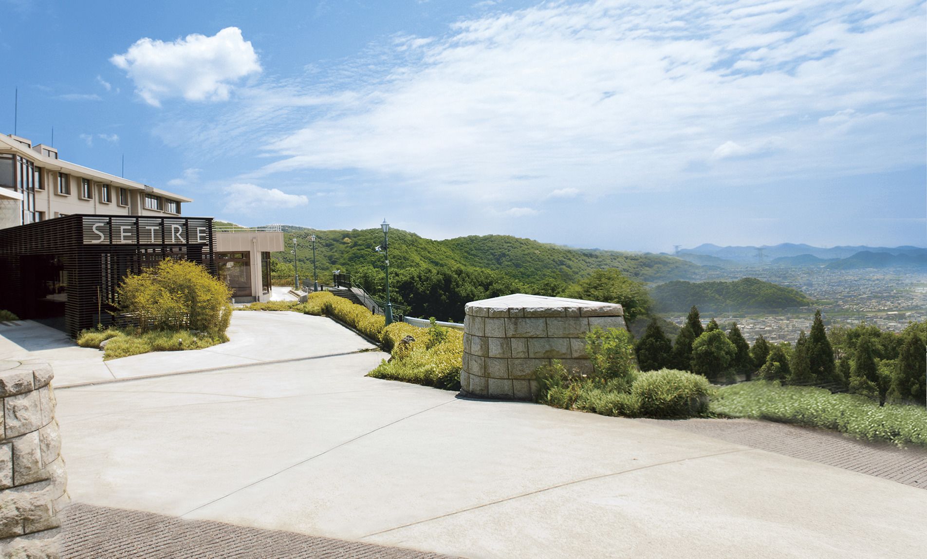 A modern building with a sign reading "SETRI" and a view of a cityscape with mountains in the background.