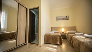 Une chambre d’hôtel avec deux lits, un plancher en bois, une porte coulissante et un tableau au mur.