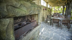 Une cheminée en pierre avec un foyer en métal, entourée de murs en pierre et recouverte d’un sol en pierre.