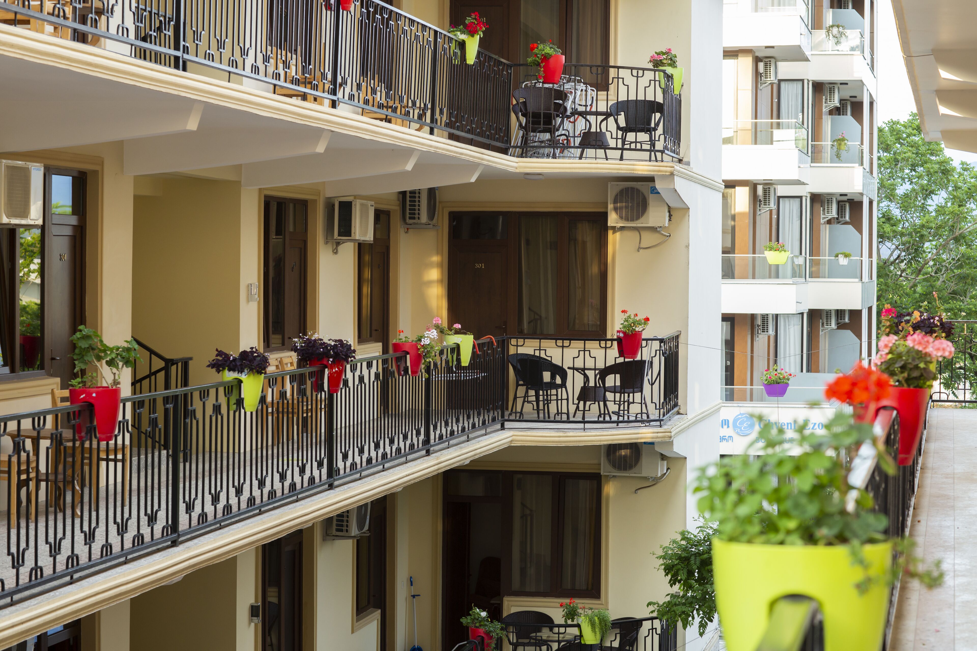 Un hotel de varios pisos con balcones, mobiliario exterior y plantas en macetas.
