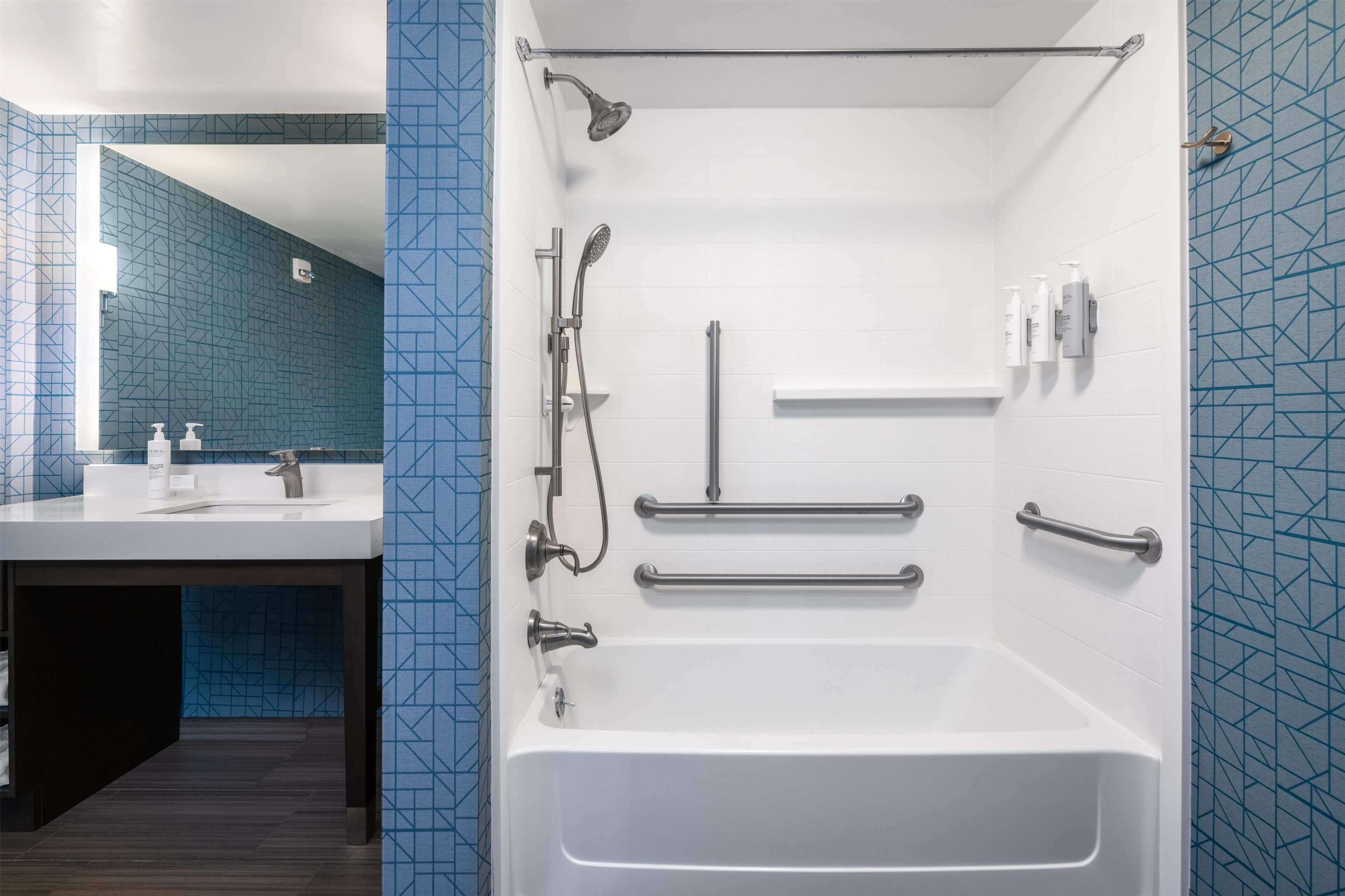 Une salle de bain équipée d’une baignoire, d’une douche et de barres d’appui.