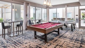 A pool table in a well-lit room with large windows, a bar area, and a casual seating arrangement. - Homewood Suites by Hilton San Jose Santa Clara (San Jose)