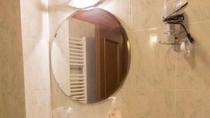 A bathroom with a white sink, a round mirror, a towel rack, and a soap dispenser on a shelf. - Florence Decamerone B&B (Florence)