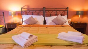A double bed with a green and orange quilt, two pillows, and two nightstands with lamps. - Florence Decamerone B&B (Florence)